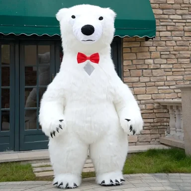 PartyBär Ein großer, weißer Teddybär mit roter Fliege steht vor einem Steinhaus.